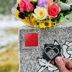 Placing a Turning Hearts medallion onto the red 3M adhesive pad on a headstone